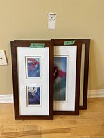 Three framed floral prints leaning against a beige wall, tagged with sizes 11x22 (x2) and 18x22.