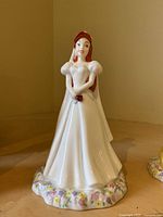 Full view of the figurine showing Ariel in a white wedding dress standing on a floral base.