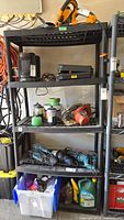 Black plastic utility shelves holding various tools and containers.