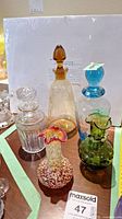 Photo of five small art glass decanters and vases on a table.