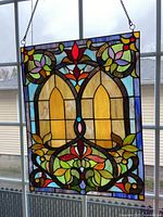Front view of rectangular stained glass panel hanging by chain in window, showing full design and colors