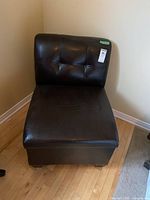 Front view of black vinyl padded storage chair showing tufted backrest and seat surface with some stains.