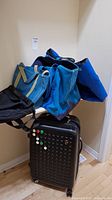 Full lot of 3 canvas travel bags stacked on top of black rolling suitcase.