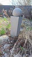 Full outdoor water fountain showing pedestal and spherical top in garden setting