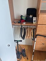 Wide view of closet shelf and floor showing air pumps, battery tender, and accessories arranged near clothing hangers