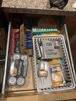 Full drawer with varied batteries and handheld lighter in a plastic basket with some individual packs visible.
