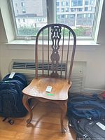 Full front view of wooden chair showing carved backrest, contoured seat, and curved cabriole legs.