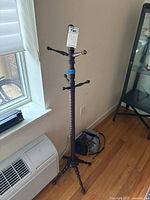 Front angle view of the dark brown wooden coat rack showing multiple arms and tripod base.