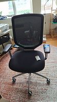 Front view of the black adjustable desk chair showing mesh backrest, padded seat, and armrests.
