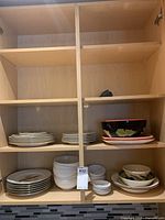 Cabinet shelves displaying stacked Wedgwood Indian Tree plates, six JKW fish dinner plates, assorted serving bowls and dishes.