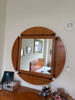 Front view showing square mirror with attached semi-circular wood panels creating circular frame.