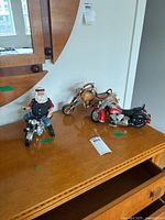All three motorcycle figures displayed on a wooden surface, showing size and grouping.