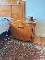 Side view of the Hickory White wooden nightstand showing cabinet doors, brass handles, and minor surface wear.