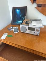 Photo showing Sangean WR-2 wooden digital radio, ThermoPro digital thermometer, framed underwater art print on wood surface.