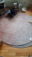 Full view of 6ft round rug showing overall shape, pattern, and condition with various objects on top not included in sale