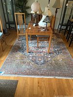 Full view of the polyester rug under a wooden dining table with chairs showing the rug's intricate pattern and rust dominant color.