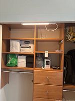 Wide view of shelving showing Depend Guards packages, humidifier in plastic bag, white and black foam blocks, and blood pressure monitor front view