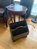 Woven two-tier magazine rack with handle, placed next to the side table, showing clean surface and structure.