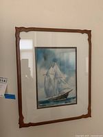 Front view of the framed signed sailboat painting with wooden frame and cream matting.