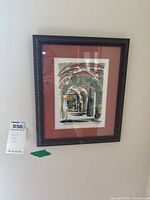 Framed signed artwork photo showing stone archway scene in a dark ornate frame with reddish mat.