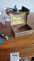 Sterling silver ring with blue stone, bull pendant on chain, and open decorative rectangular metal box with floral engravings and wooden interior base, showing tarnish.