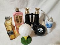 Photo showing all the items in the set: four collectible Avon bottles, eight ball, golf ball on tee, black binoculars, and pipe.
