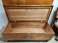 Open view of the interior of the wooden blanket chest showing its clean wood interior and metal hinge fittings under the lid.