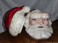 Santa head cookie jar with the lid (Santa hat) removed to show the opening.