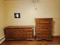 View of the tall and short wooden dressers side by side against a cream-colored wall.