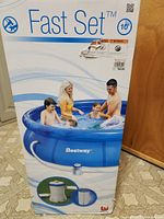 Photo of the original product box with branding, product image showing a family in the blue inflatable pool and details on the front of the box.