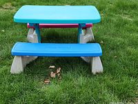 Front view of the Fisher-Price picnic table showing blue tabletop and blue bench with beige legs on grassy area.
