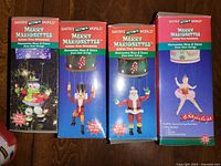 Four original retail boxes of Santa's Action World Merry Marionettes Christmas tree ornaments featuring Santa, Nutcracker, Ballerina, and Snowman characters.