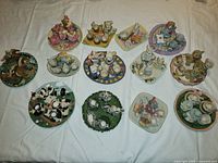 All 12 miniature animal-themed tea sets arranged on white cloth background, each set features ceramic tea cups and saucers with animal figurines in different themes