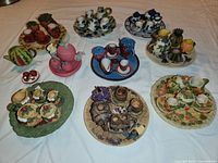 Overview of ten miniature tea sets, each fruit themed with teapots, cups, saucers, and plates arranged on a table