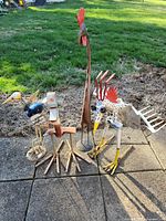 Group of five outdoor bird sculptures made with various metals including rebar, arranged on a paved patio with grass background.