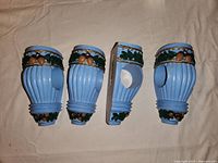 Four blue vintage-style wall sconces with ribbed sides and decorative acorn and leaf accents on top and bottom edges.