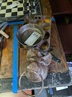 Photo showing cast iron mini fry pan, muffin pans, and pig head door knocker on wooden table