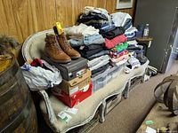 Stack of folded clothes and shoe boxes on a bench in a room with wood panel walls