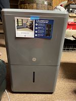 Front view of GE grey dehumidifier with GE logo and water tank window.