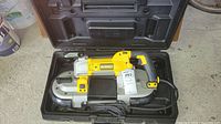 Top-down view of DeWalt band saw seated in plastic case, power cord coiled