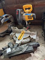 Front view of DeWalt DW713 miter saw with dust shield and adapter on floor in garage.