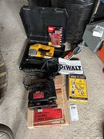 Dewalt DW318 jig saw in open black plastic case with instruction manual and accessories. Sears Craftsman scroll saw in original cardboard box on floor.