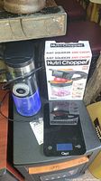 Photo showing Krups coffee grinder, Nutri Chopper box, and Ozeri digital scale stacked together