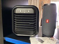 Photo showing side-by-side view of the personal air cooler and JBL portable speaker with manual.