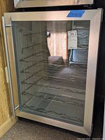 Front view of GE Monogram wine fridge showing stainless steel frame, glass door, and wire racks.