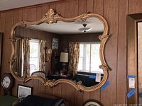 Full front view of the mirror hung on a wood-paneled wall showing overall shape and size