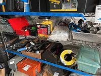 Metal shelving with various hardware including red toolbox, hooks, hammers, tape spool