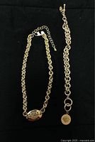 Full view of Harley Davidson necklace and bracelet on black background showing chain style and emblems.