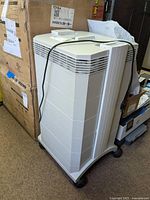 Full view of the IQAir air cleaner unit showing its white plastic body with multiple vents and wheels at the base.