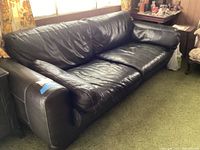 Front view of black leather sofa in living room setting